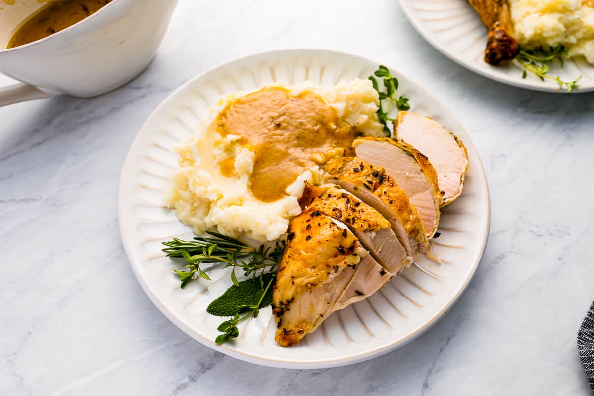 A plate with roasted chicken, mashed potatoes, and gravy on it.