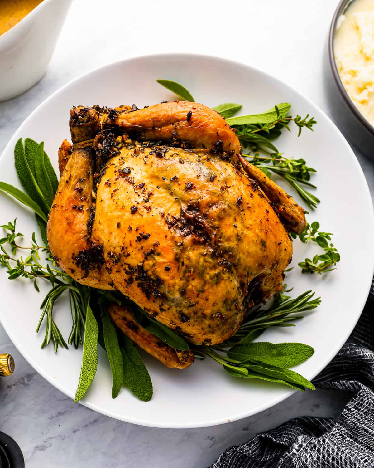 Roasted Thanksgiving chicken on a plate with gravy and sprigs of thyme.