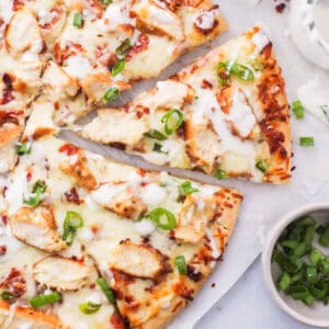 a cut chicken bacon ranch pizza on parchment.