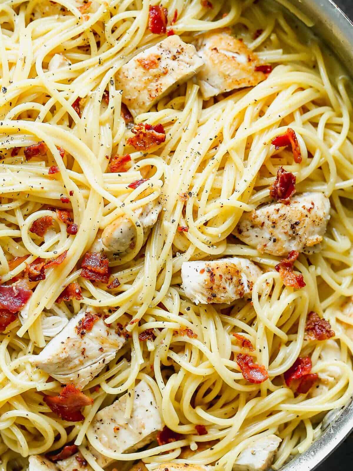 up close image of pasta with cream sauce, bacon, and chicken