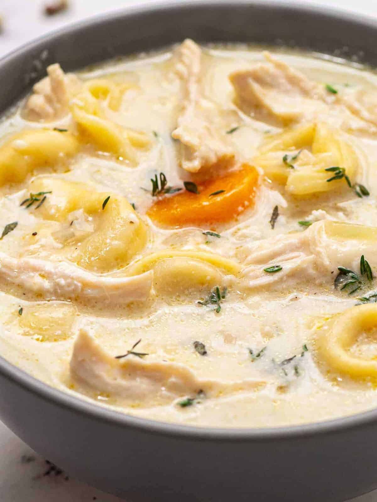 up close image of creamy chicken tortellini soup in gray bowl