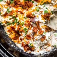 closeup view of crack chicken in a crockpot with a serving spoon.