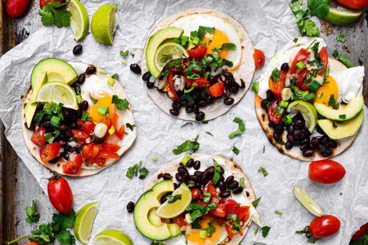 Tacos with black beans, avocado, tomatoes and limes.
