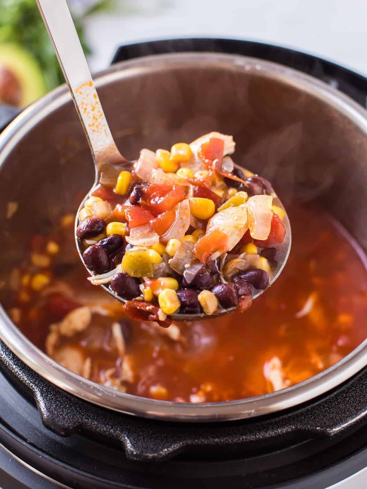 ladle lifting up chicken chili from instant pot