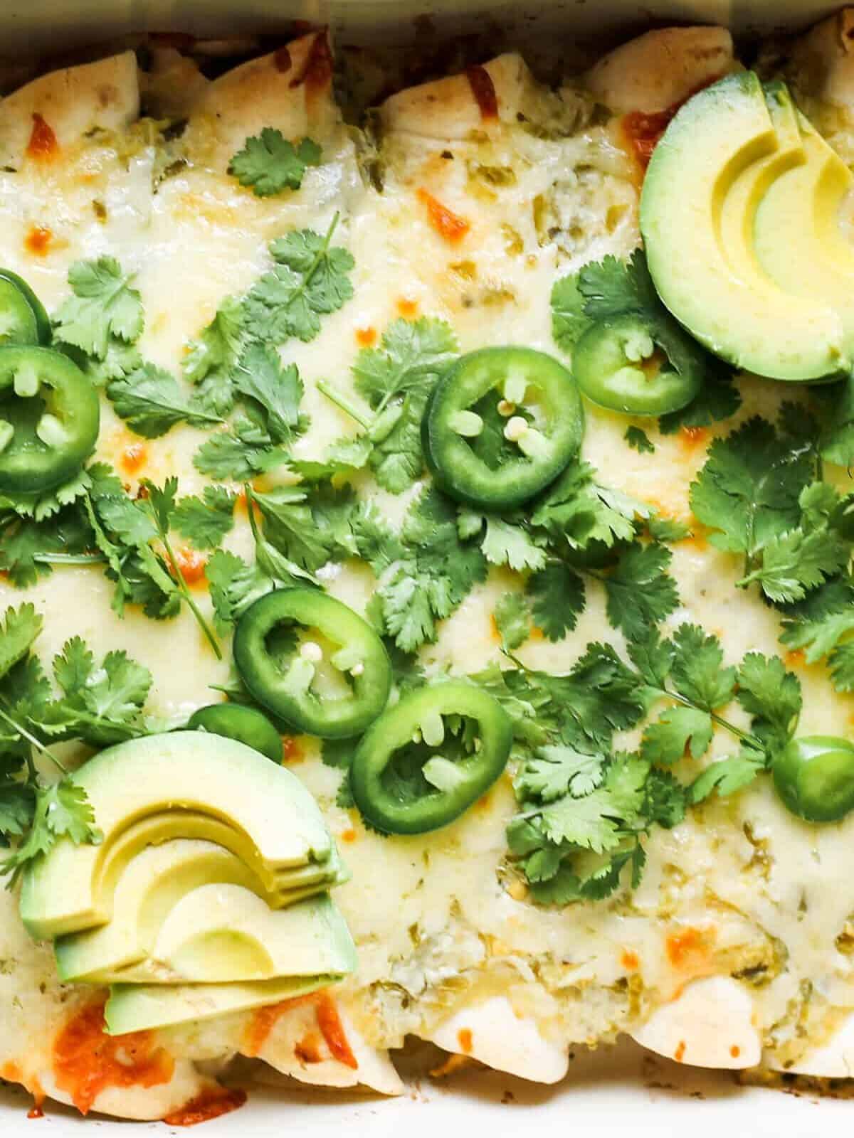 up close image of green chile salsa verde chicken enchiladas in pan