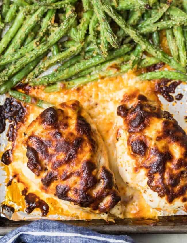 Pesto Mozzarella Chicken with green beans on a baking sheet.