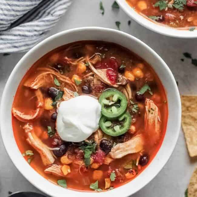 Mexican chicken soup with sour cream and tortilla chips, reminiscent of Chicken Enchilada Soup.