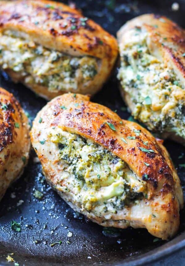 four broccoli and cheese stuffed chicken breasts cooked in a skillet.