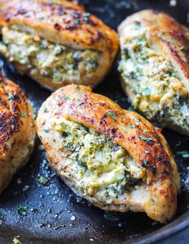 four broccoli and cheese stuffed chicken breasts cooked in a skillet.