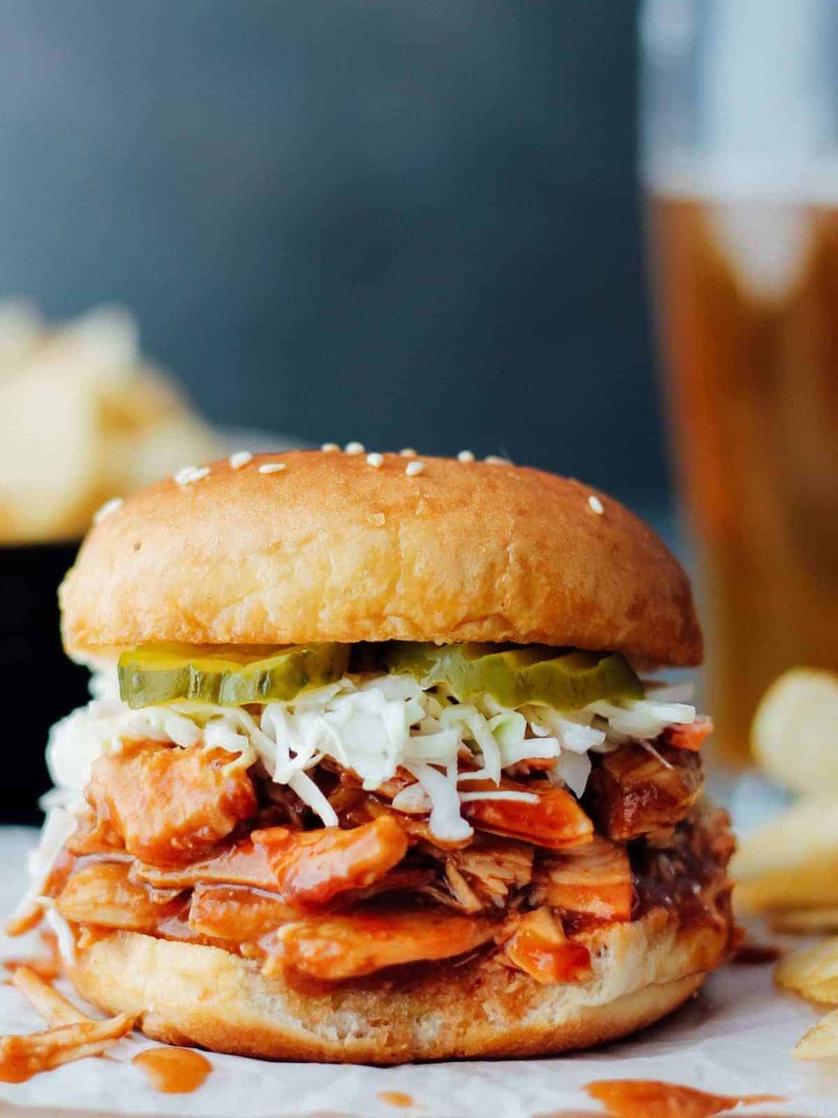 a crockpot bbq pulled pork sandwich served with fries and pickles.
