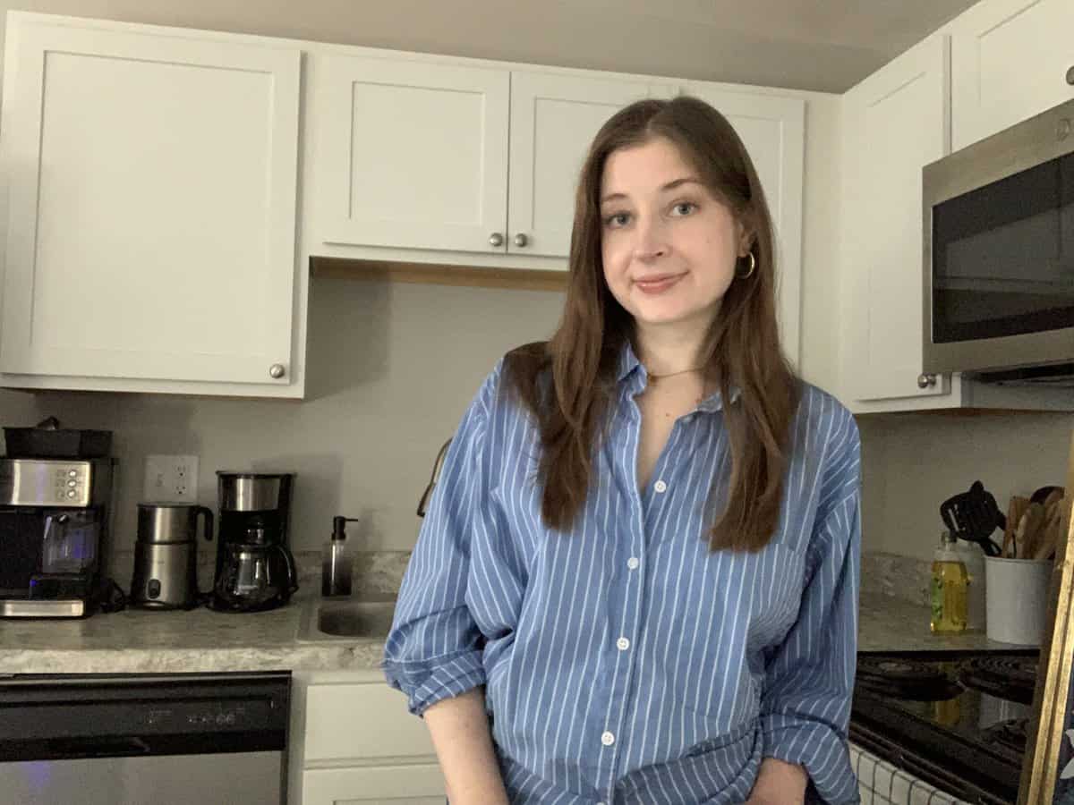 A woman in a blue shirt standing in a kitchen.