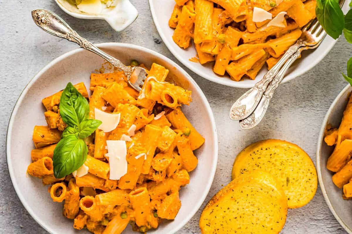 chicken rigatoni in white bowls with forks.