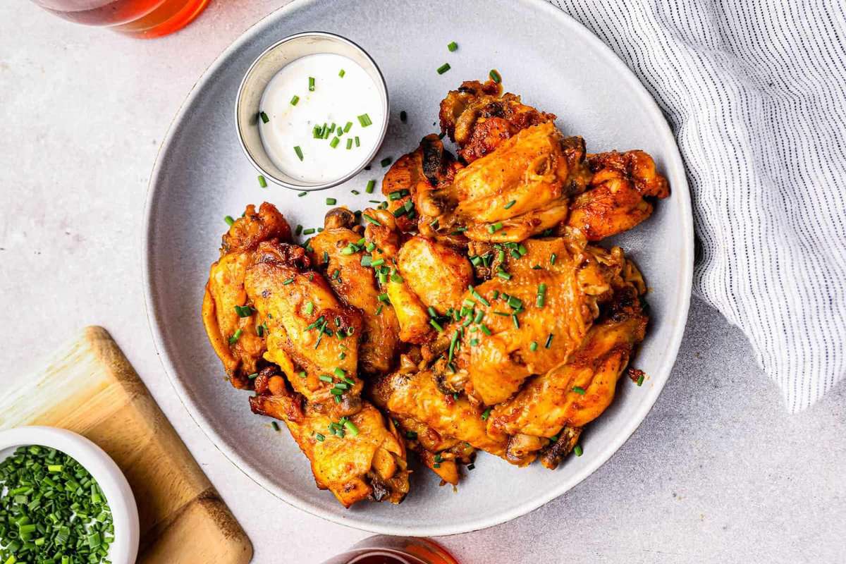 crockpot buffalo chicken wings on a white plate with ranch.