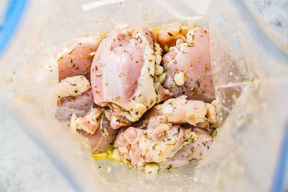 looking into a plastic bag filled with chicken thighs in a greek marinade