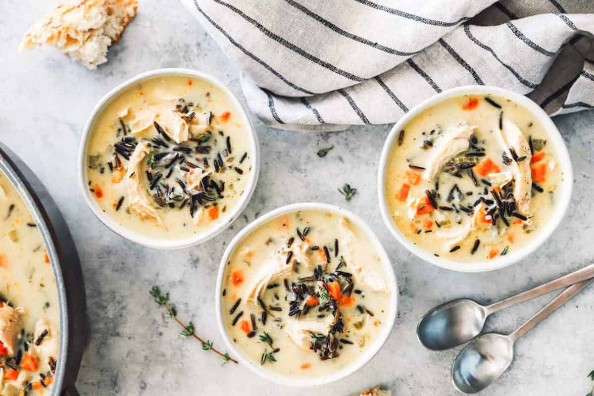 overhead image of 3 bowls of chicken wild rice soup in white bowls