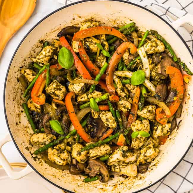 overhead view of basil chicken and vegetables in a white pan.