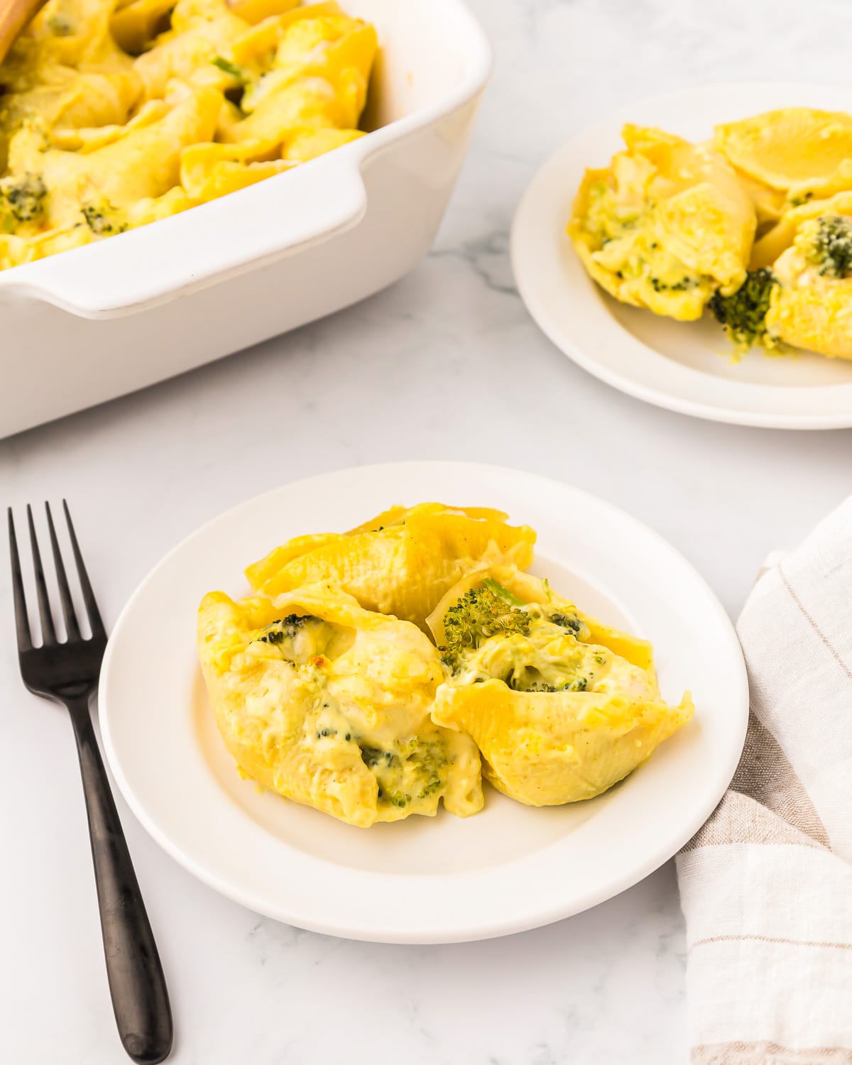 a serving of chicken and broccoli stuffed shells on a white plate with a fork.