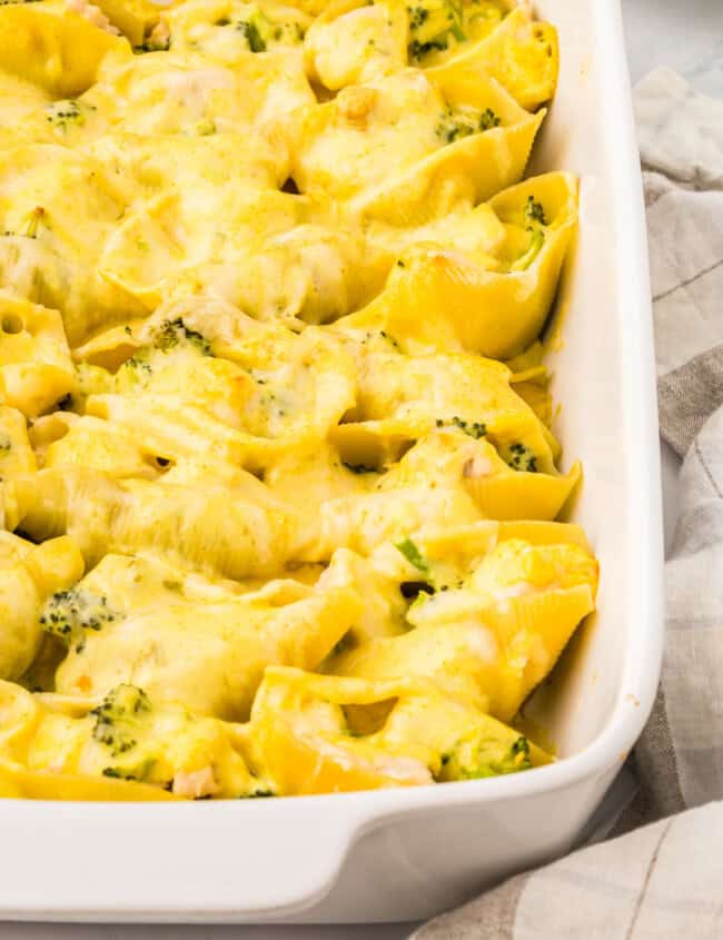 close up view of chicken and broccoli stuffed shells in a white casserole dish.