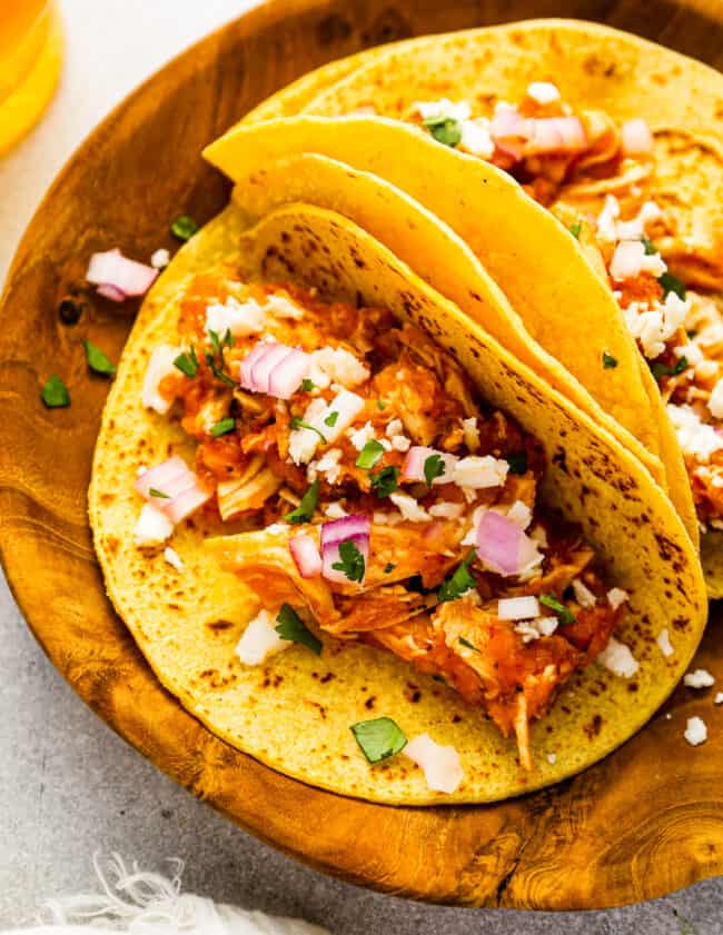 chicken tinga tacos on a wooden plate.