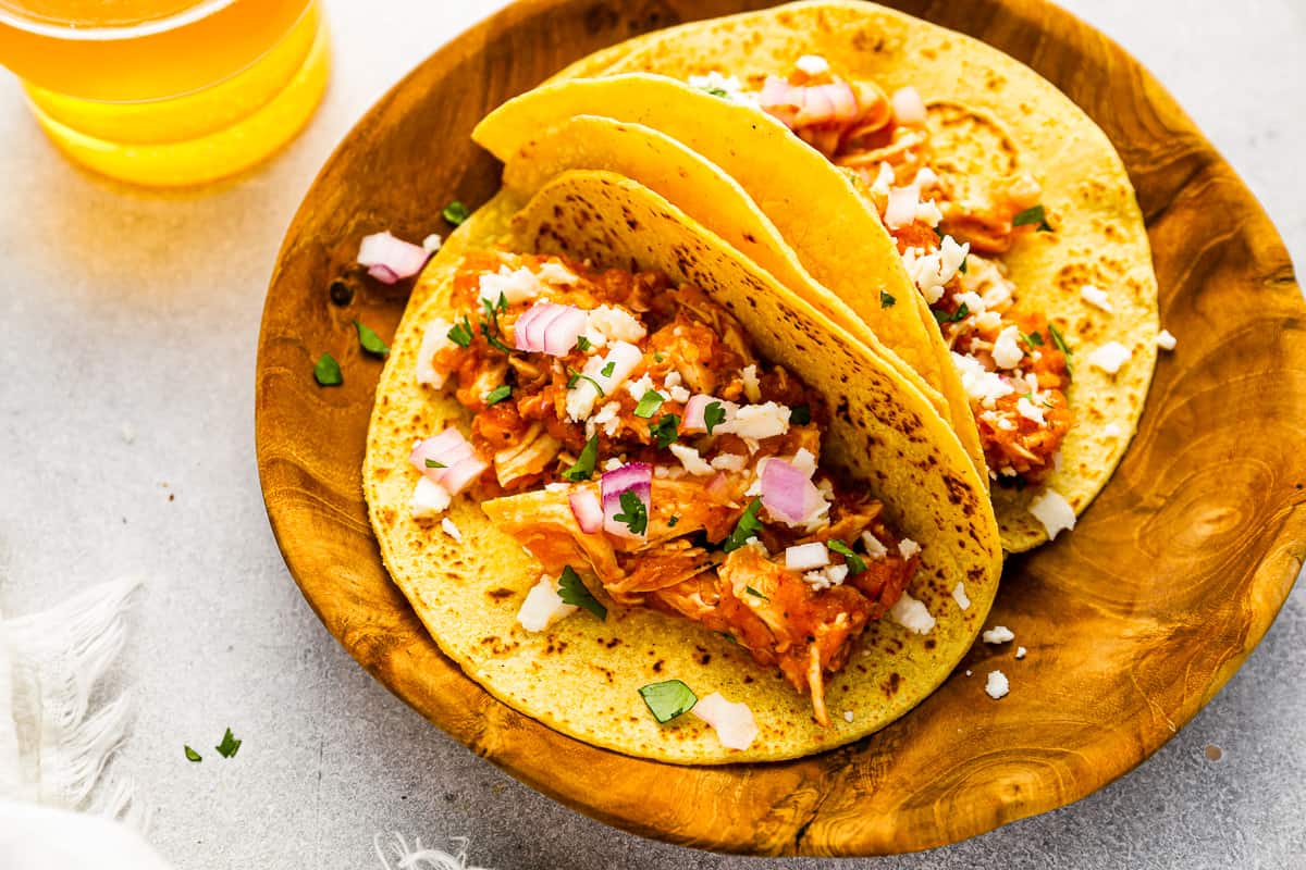 chicken tinga tacos on a wooden plate.