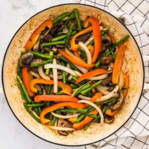 sauteed vegetables in a white pan.