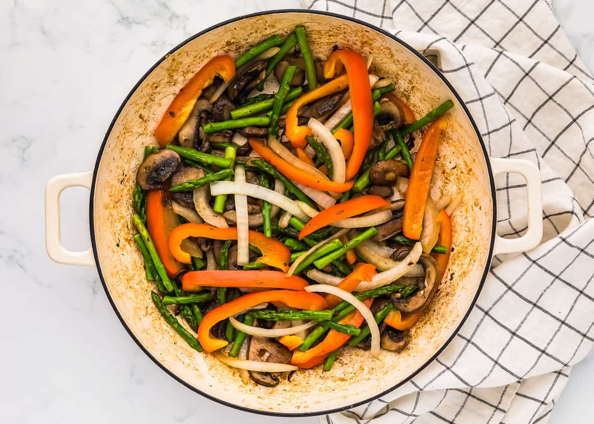 sauteed vegetables in a white pan.