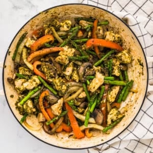 basil chicken with vegetables in a white pan.