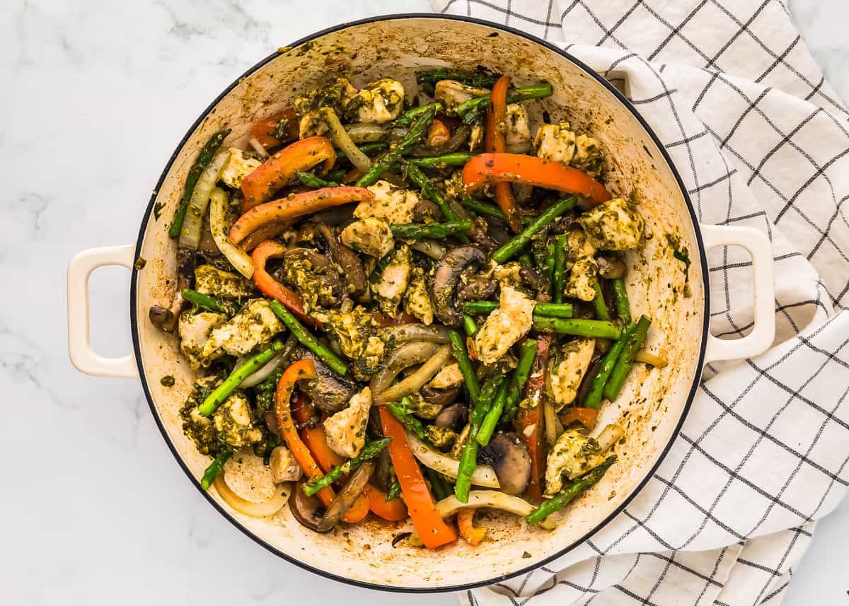 basil chicken with vegetables in a white pan.