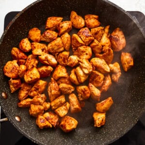 seasoned chicken chunks in a frying pan.