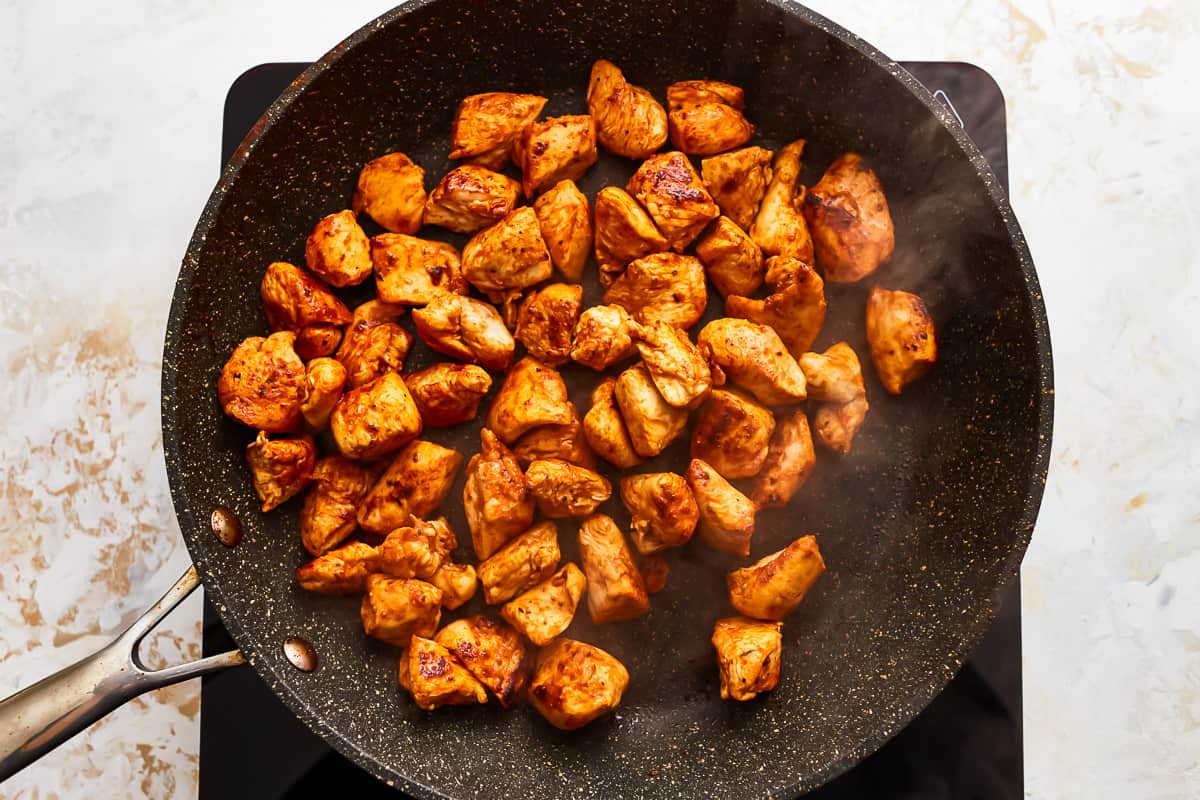 seasoned chicken chunks in a frying pan.