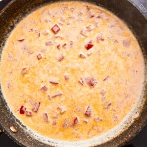 creamy orange sauce with onion in a frying pan.