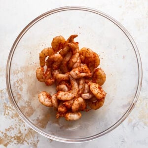 seasoned raw shrimp in a glass bowl.