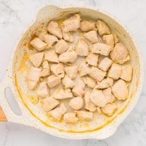 chunks of chicken cooking in a pan.