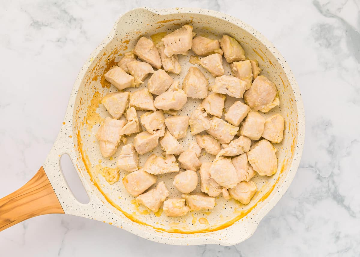 chunks of chicken cooking in a pan.