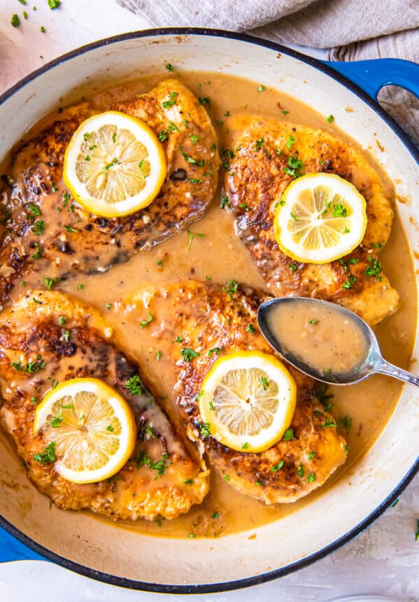 overhead view of chicken francese in a pan with a spoon.