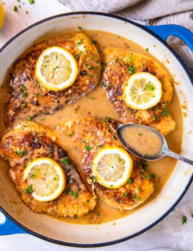 overhead view of chicken francese in a pan with a spoon.