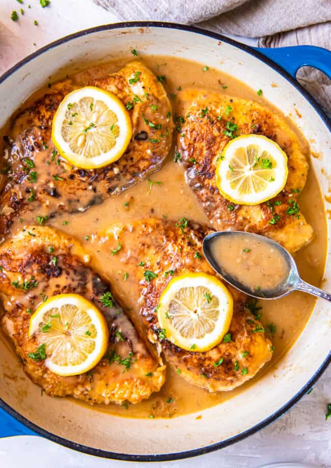 overhead view of chicken francese in a pan with a spoon.