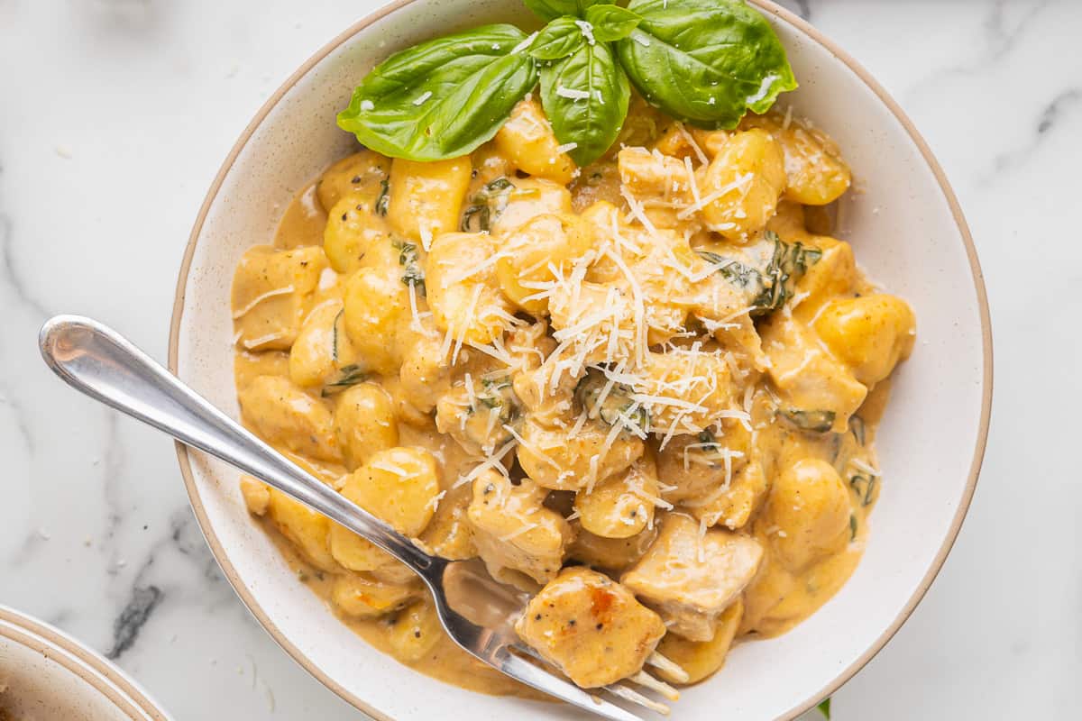 overhead view of creamy chicken gnocchi in a bowl with a fork.