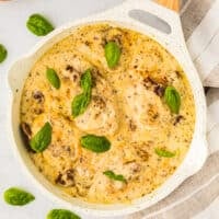 overhead view of marry me chicken topped with fresh basil leaves in a white pan.