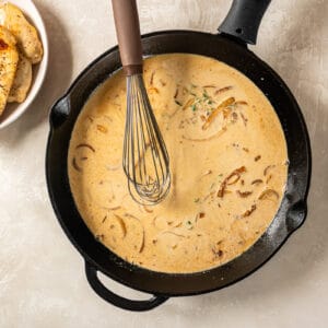 dijon mustard sauce in a cast iron pan with a whisk.
