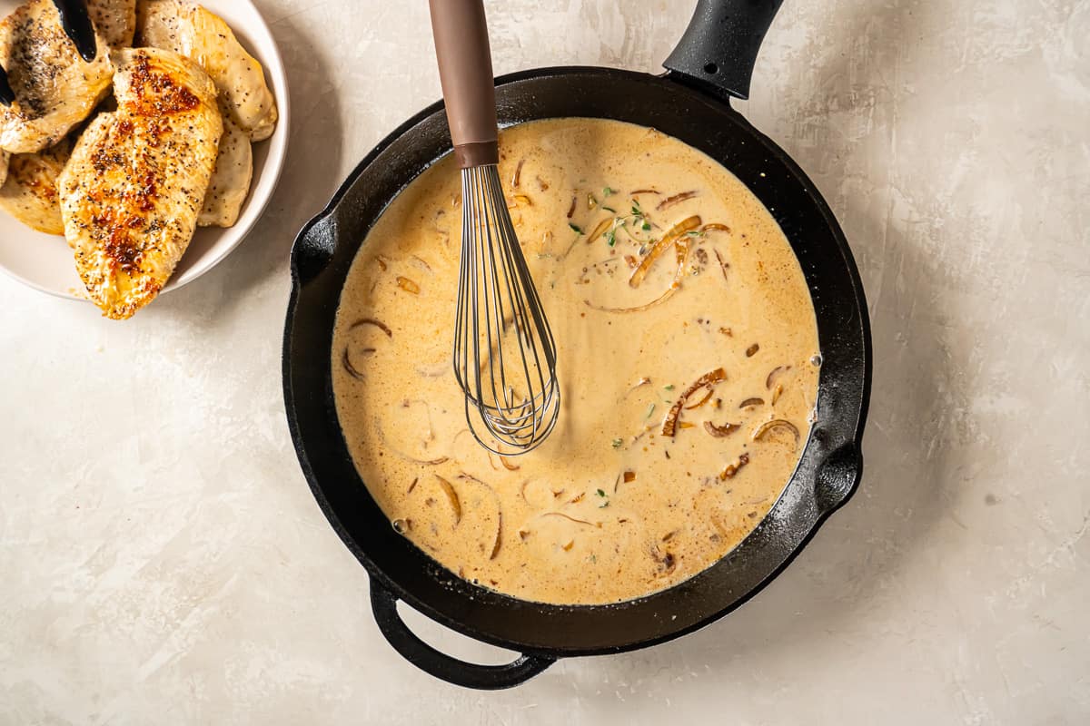 dijon mustard sauce in a cast iron pan with a whisk.