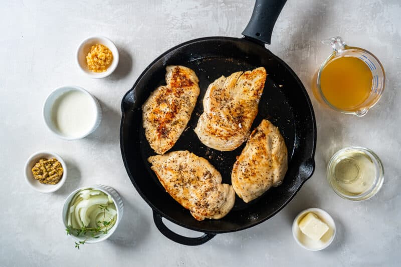 overhead view of 4 cooked chicken breasts in a cast iron pan.