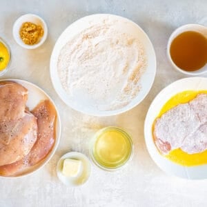 dredged chicken dipped in egg in a white bowl.