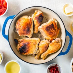 cooked chicken leg quarters in a blue pan.