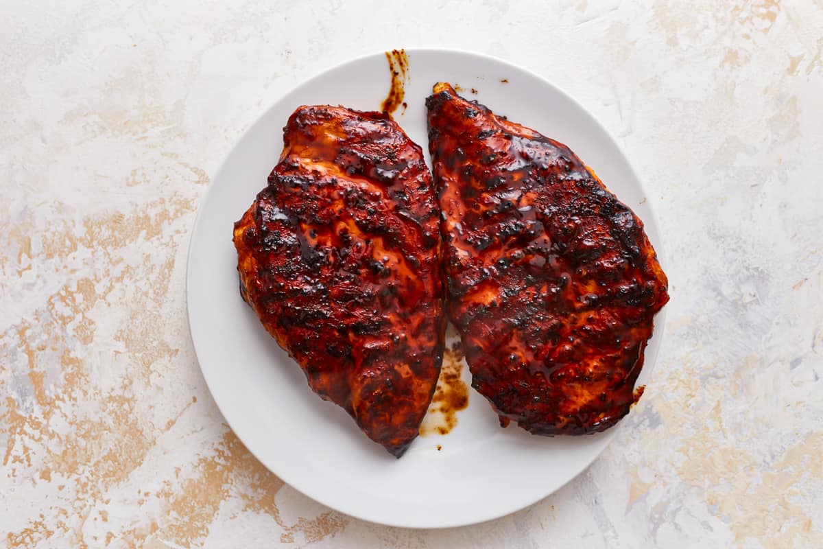 2 grilled chicken breasts on a white plate.