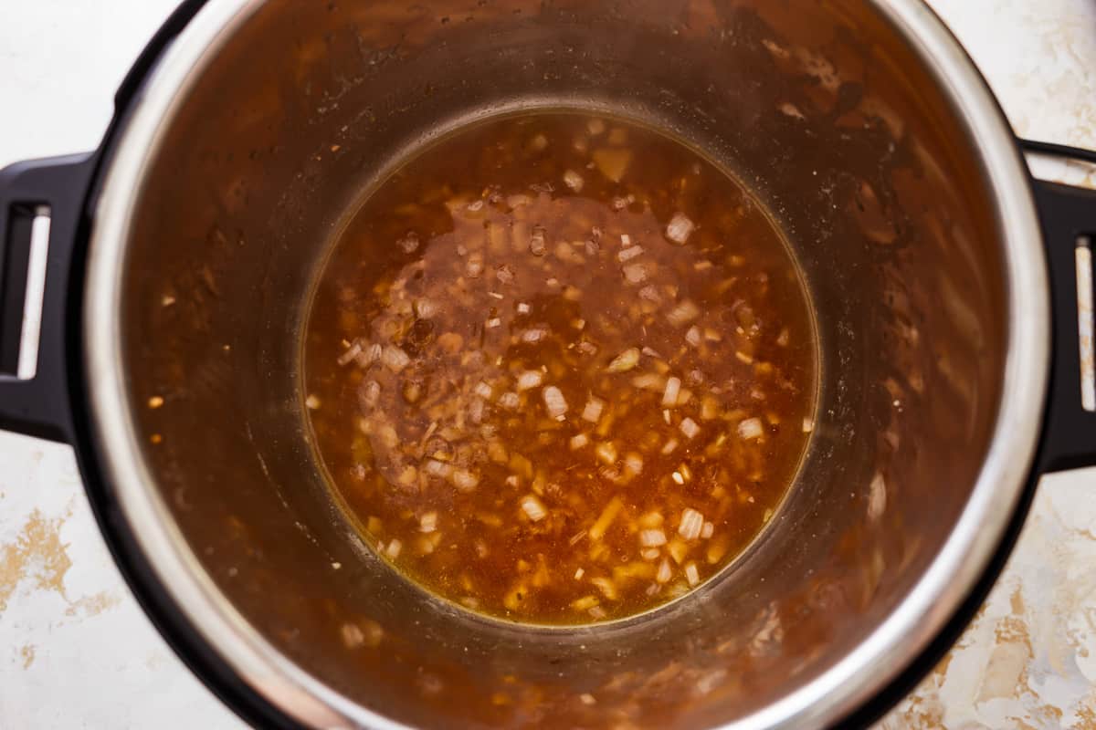 deglazing an instant pot with chicken broth.