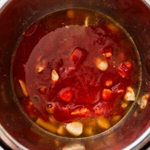 tomato sauce poured over vegetables and chicken in an instant pot.