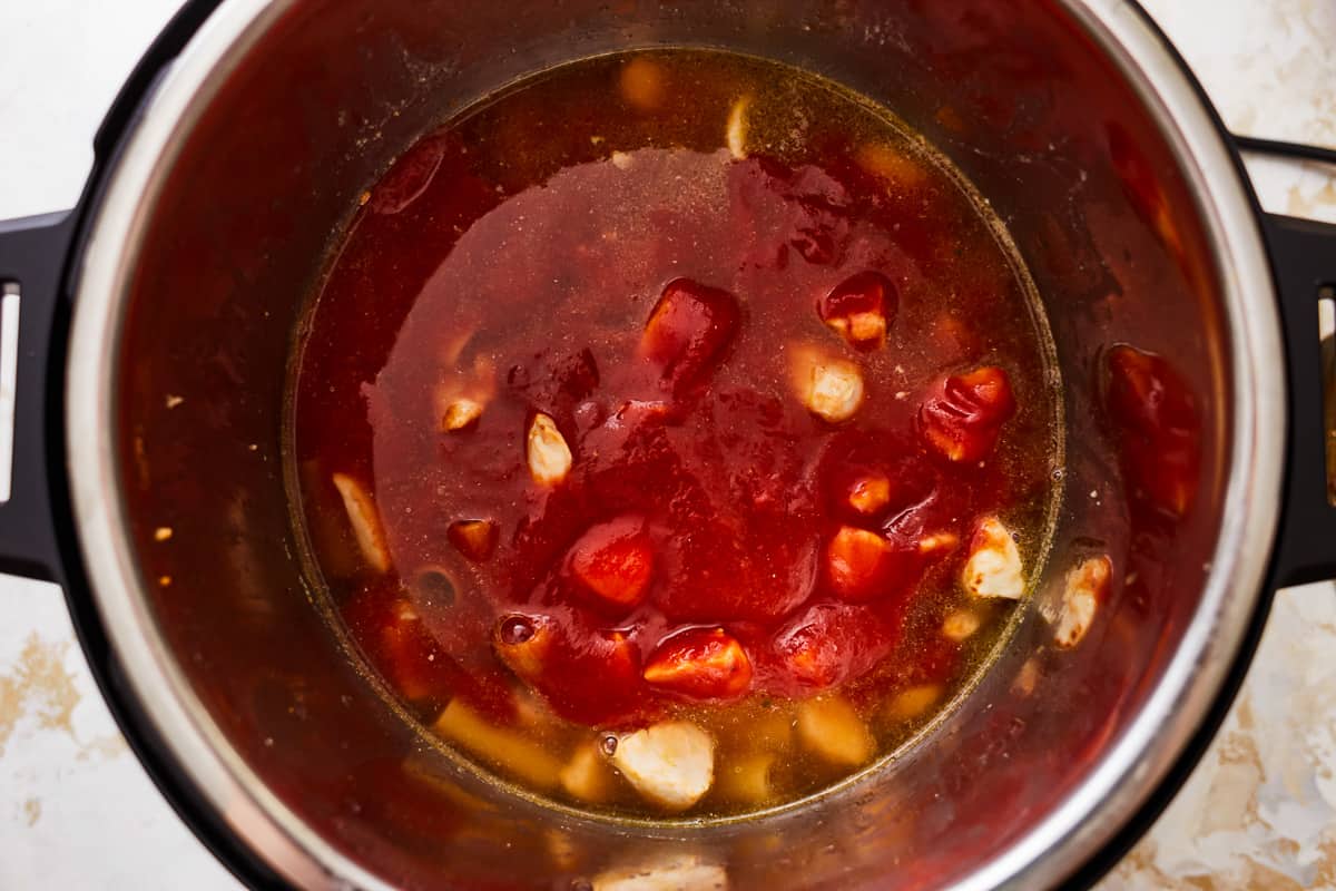 tomato sauce poured over vegetables and chicken in an instant pot.