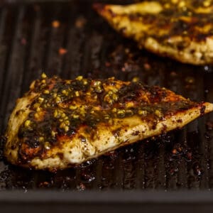 grilled pesto chicken breasts on a grill.