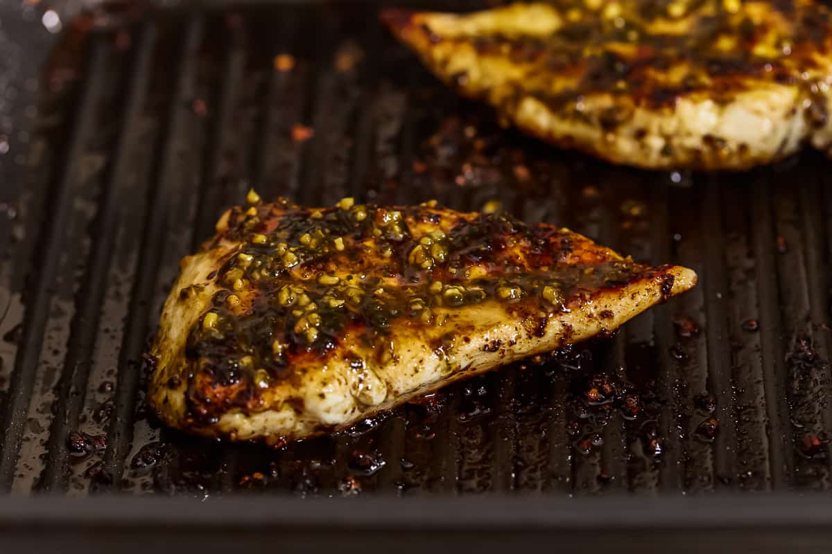 grilled pesto chicken breasts on a grill.